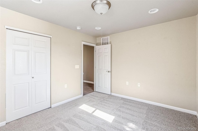 unfurnished bedroom featuring a closet, carpet flooring, visible vents, and baseboards