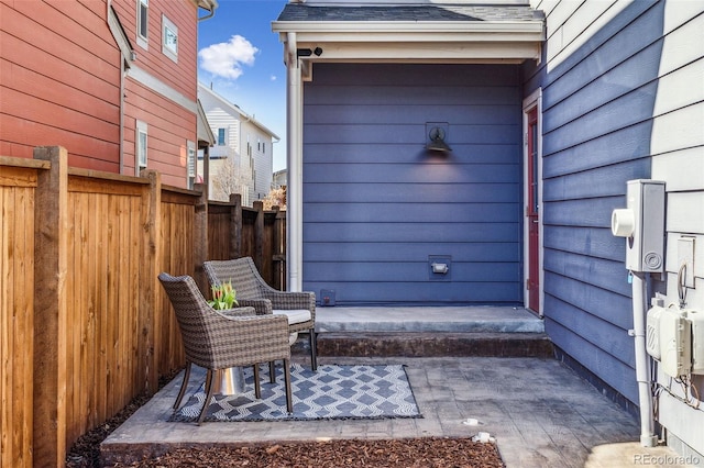 property entrance with roof with shingles and fence