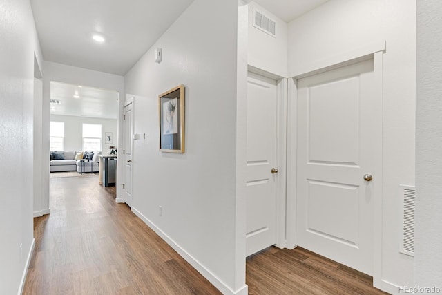 hall featuring dark wood finished floors, baseboards, and visible vents