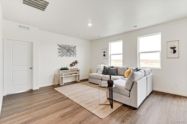 living area with wood finished floors, visible vents, and baseboards