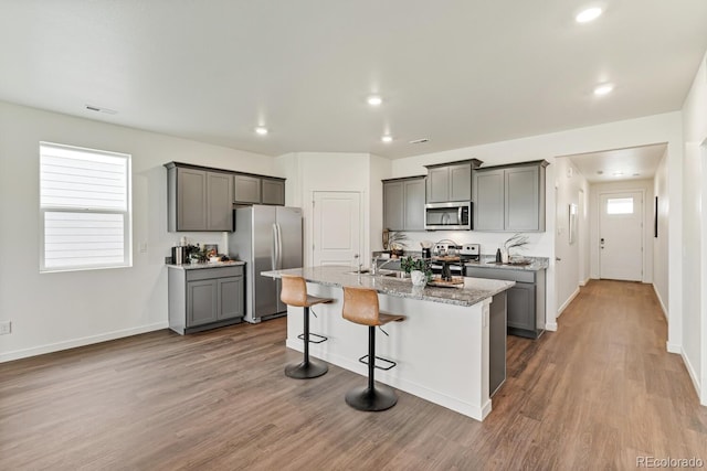 kitchen featuring a kitchen island with sink, appliances with stainless steel finishes, and gray cabinetry