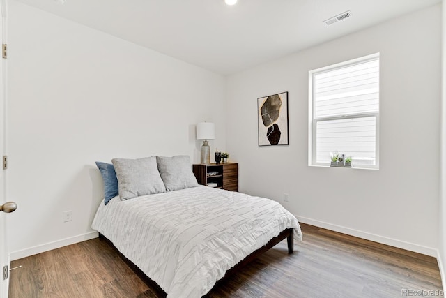 bedroom featuring wood finished floors, visible vents, and baseboards