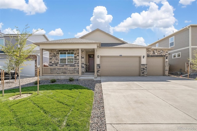 view of front of house with a front yard, an attached garage, covered porch, concrete driveway, and stone siding