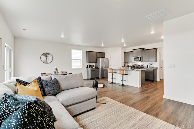 living area featuring visible vents, recessed lighting, baseboards, and wood finished floors