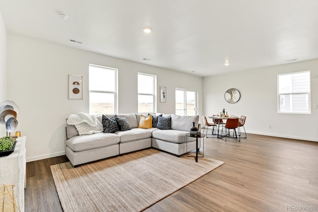 living area with recessed lighting, wood finished floors, visible vents, and baseboards