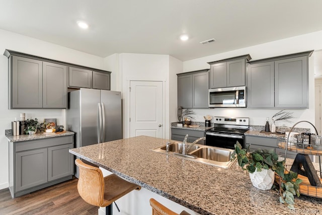 kitchen with visible vents, gray cabinetry, a sink, stainless steel appliances, and dark wood-style flooring