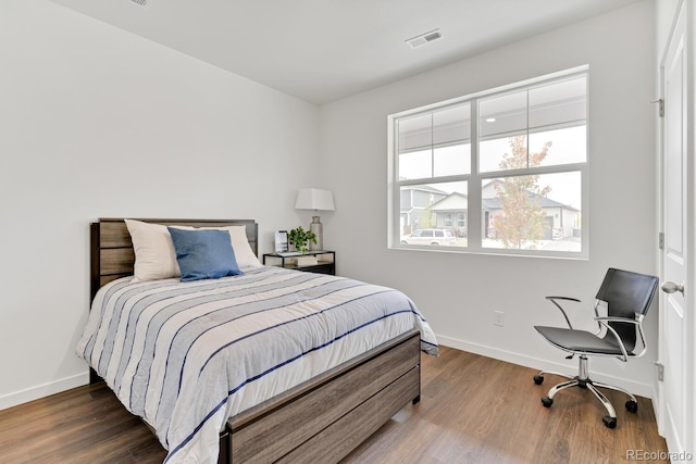 bedroom featuring visible vents, baseboards, and wood finished floors