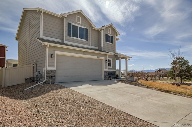 view of property exterior with fence, stone siding, a garage, and driveway