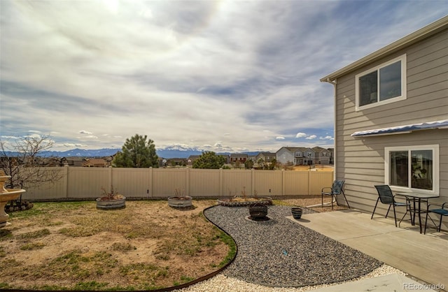 view of yard with a mountain view, a patio area, fence, and a fire pit