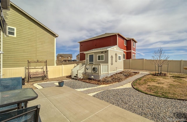 view of side of home featuring an outbuilding, a fenced backyard, and a patio area