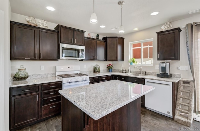 kitchen with a sink, dark brown cabinets, white appliances, and dark wood-style floors