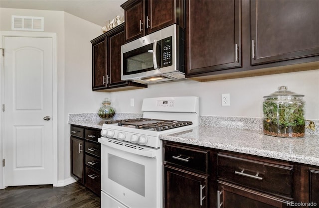 kitchen with visible vents, stainless steel microwave, white gas range, and light stone counters