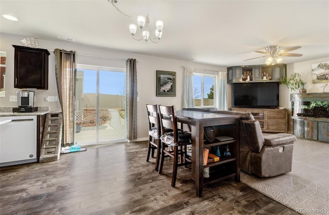 dining space with ceiling fan with notable chandelier, dark wood-style flooring, and visible vents