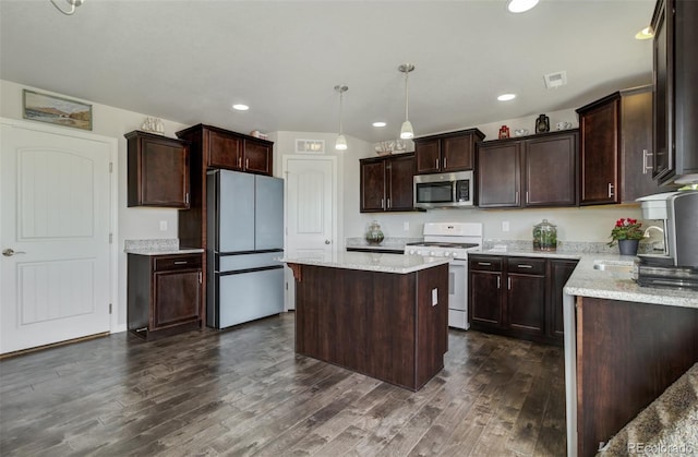 kitchen featuring stainless steel microwave, white gas range oven, freestanding refrigerator, visible vents, and a sink