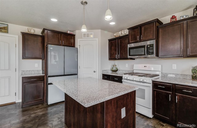 kitchen featuring stainless steel microwave, dark wood-style flooring, white gas range oven, visible vents, and fridge