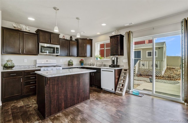 kitchen featuring dark wood-style floors, a kitchen island, white appliances, and dark brown cabinetry