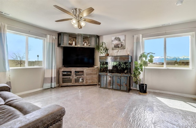 living area featuring baseboards, a ceiling fan, and visible vents