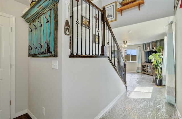 stairway featuring baseboards and a ceiling fan