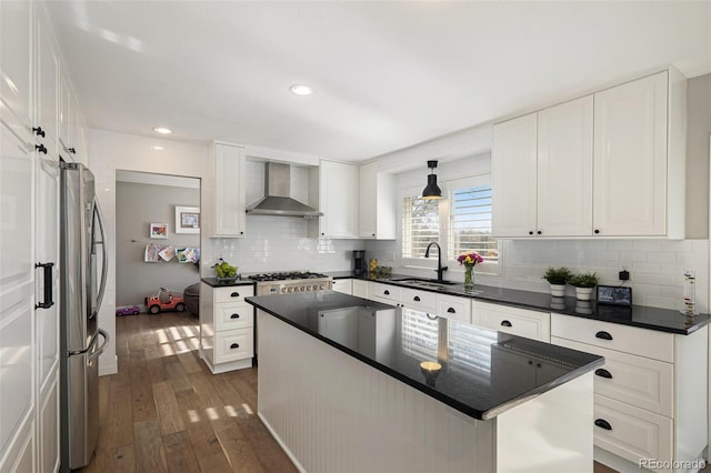 kitchen with dark wood-style flooring, a sink, white cabinetry, dark countertops, and wall chimney range hood