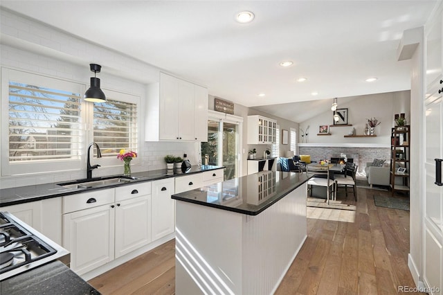 kitchen with a sink, light wood-type flooring, and dark countertops