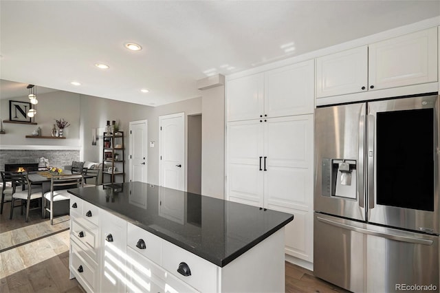 kitchen featuring stainless steel fridge with ice dispenser, a lit fireplace, recessed lighting, white cabinetry, and dark wood-style flooring