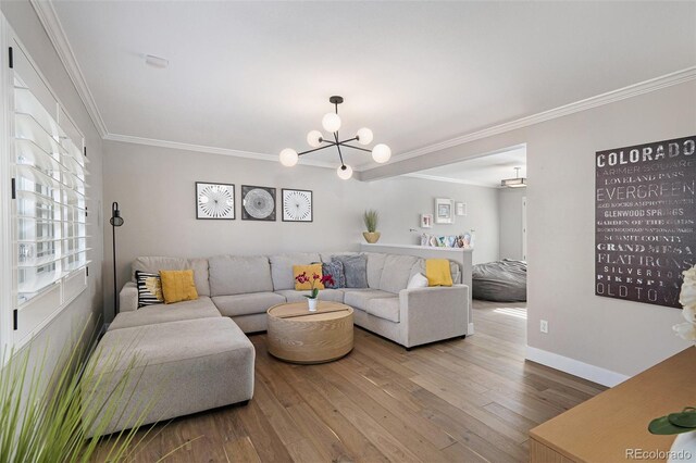 living area with baseboards, a notable chandelier, wood finished floors, and ornamental molding