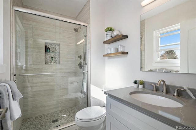 bathroom featuring a stall shower, toilet, and vanity