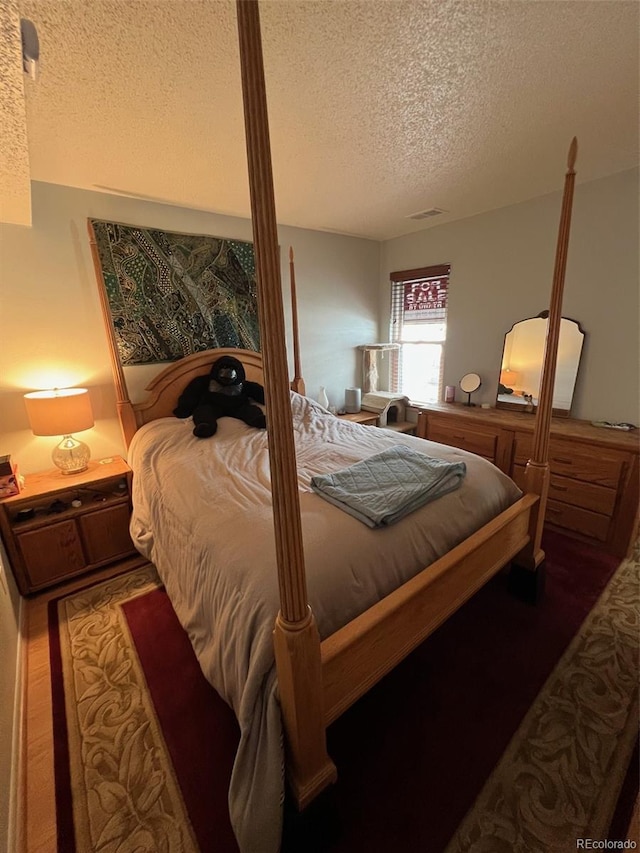 bedroom with a textured ceiling and wood finished floors