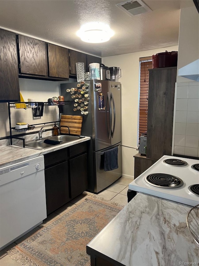 kitchen with a sink, a textured ceiling, visible vents, white appliances, and light countertops
