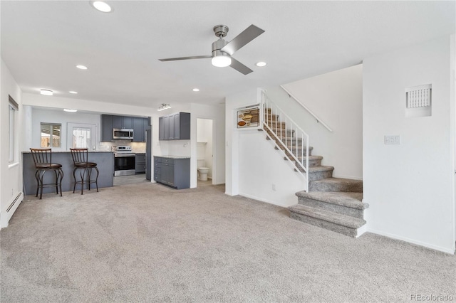 carpeted living room featuring a baseboard heating unit and ceiling fan