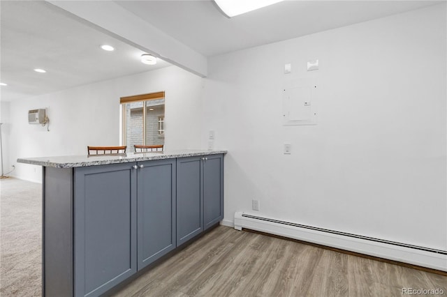 interior space with an AC wall unit, a baseboard radiator, gray cabinets, kitchen peninsula, and hardwood / wood-style floors