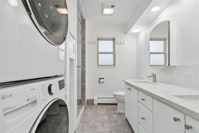 bathroom featuring stacked washing maching and dryer, decorative backsplash, vanity, a baseboard heating unit, and toilet