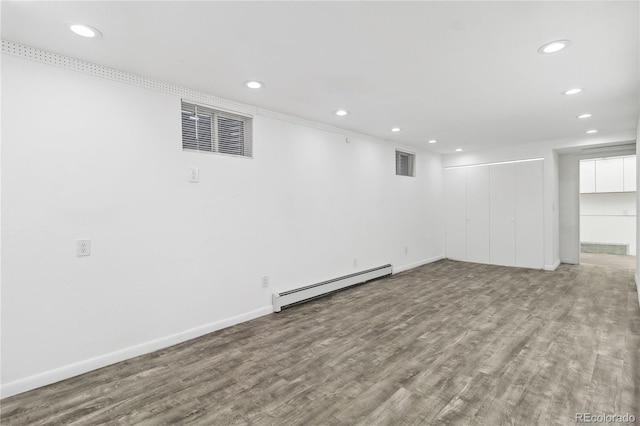 basement featuring a baseboard heating unit and hardwood / wood-style floors