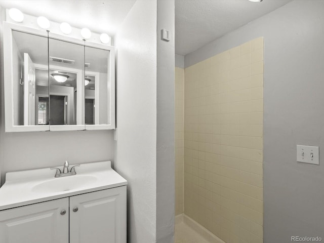 4858 S Quintero Cir, Aurora, CO 80015 - bathroom with vanity, tiled shower, and a textured ceiling