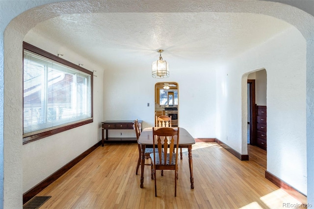 dining space with a textured ceiling and light hardwood / wood-style flooring