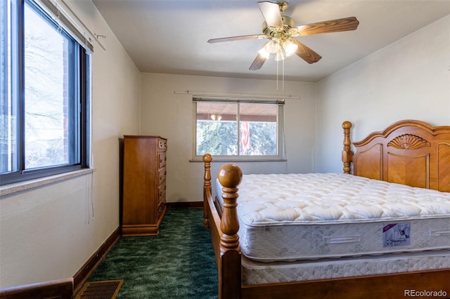 bedroom with ceiling fan, multiple windows, and dark colored carpet