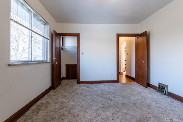 unfurnished bedroom with light colored carpet and a closet