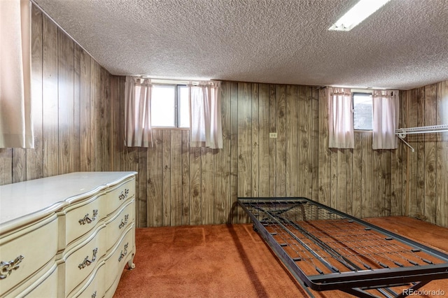 unfurnished bedroom featuring a textured ceiling, multiple windows, carpet, and wooden walls