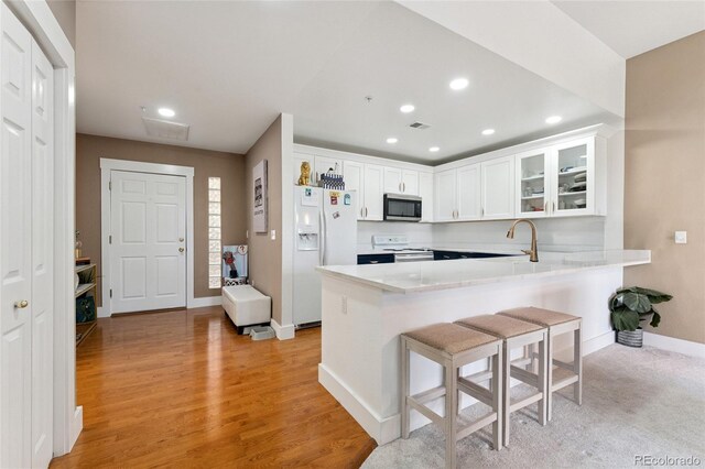 6000 W Floyd Ave Unit 214, Denver, CO 80227 - kitchen with white appliances, a peninsula, glass insert cabinets, white cabinets, and recessed lighting