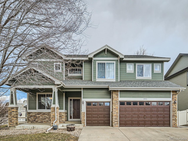 view of front of home with stone siding, roof with shingles, driveway, and an attached garage