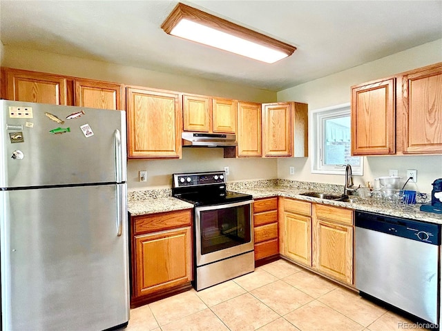 kitchen featuring light stone countertops, appliances with stainless steel finishes, a sink, light tile patterned floors, and under cabinet range hood