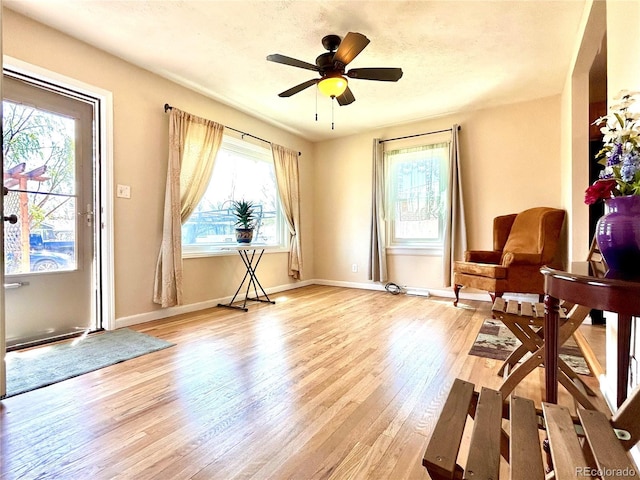 sitting room featuring baseboards, ceiling fan, and light wood-type flooring