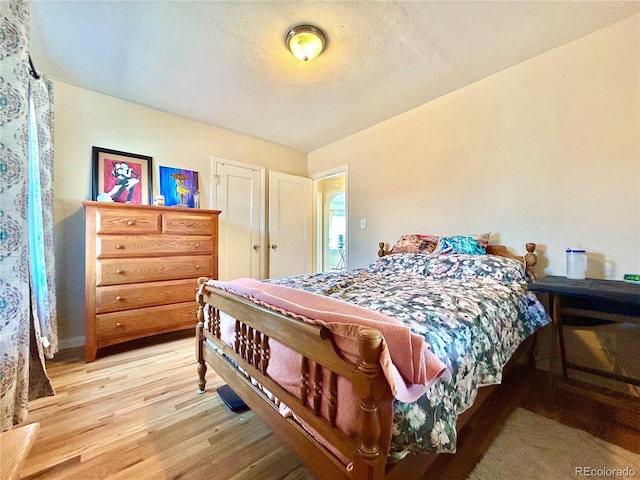 bedroom with light wood-style floors and a textured ceiling