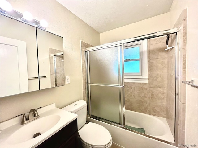 bathroom featuring toilet, combined bath / shower with glass door, and vanity