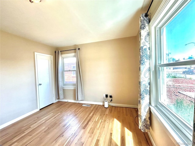 unfurnished room with baseboards, light wood-style flooring, and visible vents