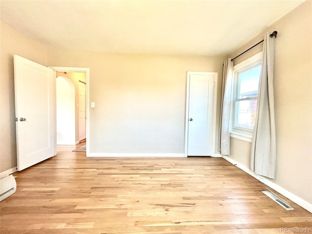 unfurnished room featuring baseboards, visible vents, and light wood finished floors