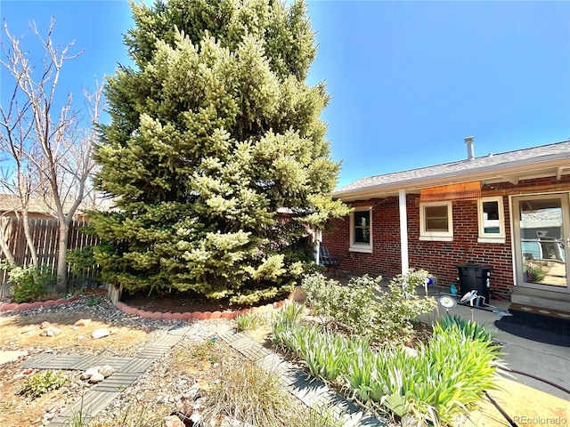 rear view of property featuring brick siding and fence