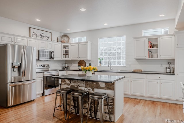 8367 Devinney St, Arvada, CO 80005 - kitchen with stainless steel appliances, a sink, a breakfast bar, dark countertops, and recessed lighting