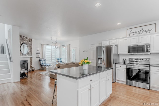 8367 Devinney St, Arvada, CO 80005 - kitchen with stainless steel appliances, a chandelier, a kitchen island, white cabinetry, and a kitchen bar
