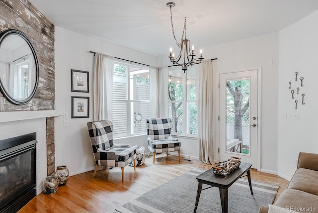 8367 Devinney St, Arvada, CO 80005 - living room with healthy amount of natural light, a chandelier, wood finished floors, and a brick fireplace